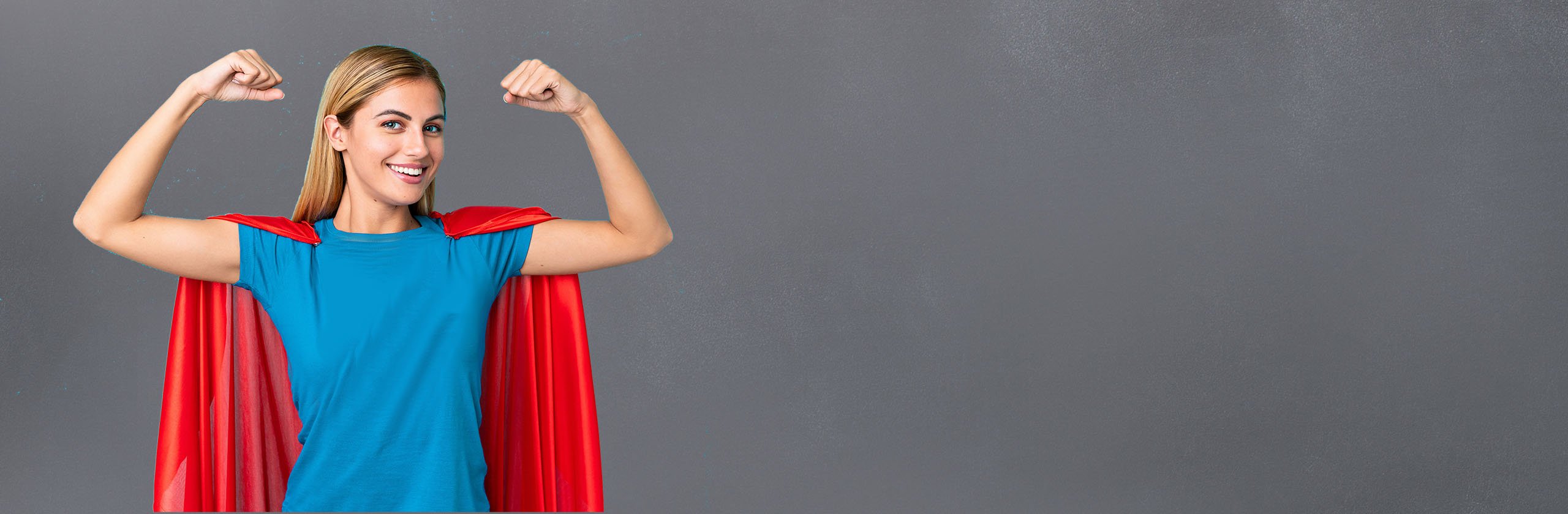 Junge Frau mit rotem Superman-Umhang in Heldenposition